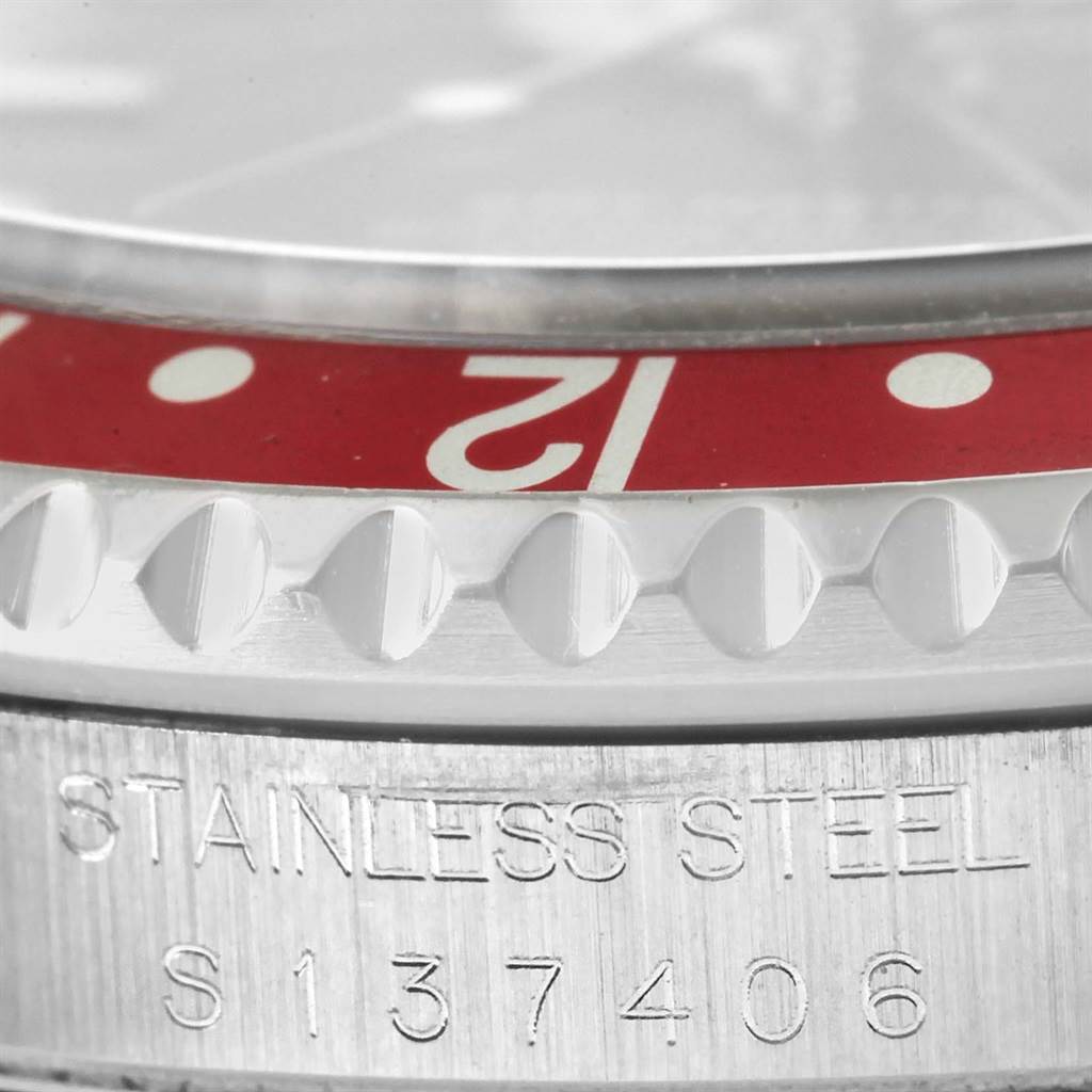 This close-up of a Rolex GMT-Master 16710 Men's Stainless Steel Black Dial 16710 Men's Stainless Steel Black Dial watch shows the stainless steel casing, part of the bezel, and part of the serial number.