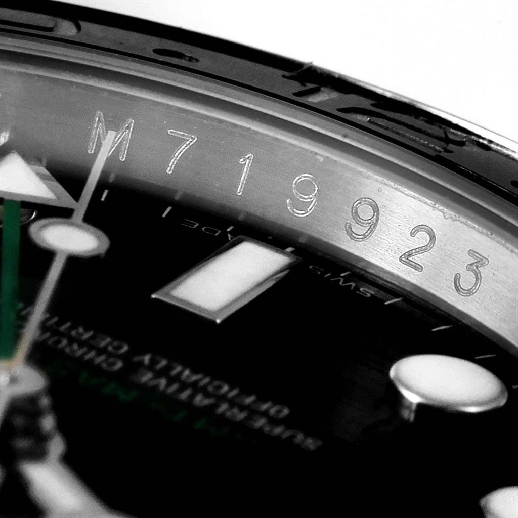 This close-up image of a Rolex GMT-Master 116710 Men's Stainless Steel Black Dial 116710 Men's Stainless Steel Black Dial watch shows its engraved serial number and part of the dial and hands.
