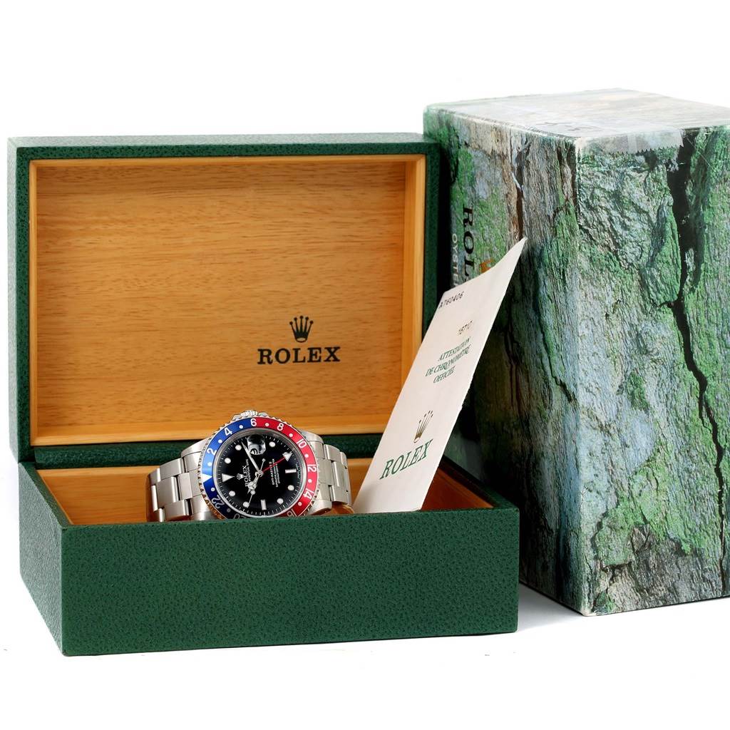 The Rolex GMT-Master 16710 Men's Stainless Steel Black Dial 16710 Men's Stainless Steel Black Dial watch is displayed inside its open green box with the manual leaning to one side.