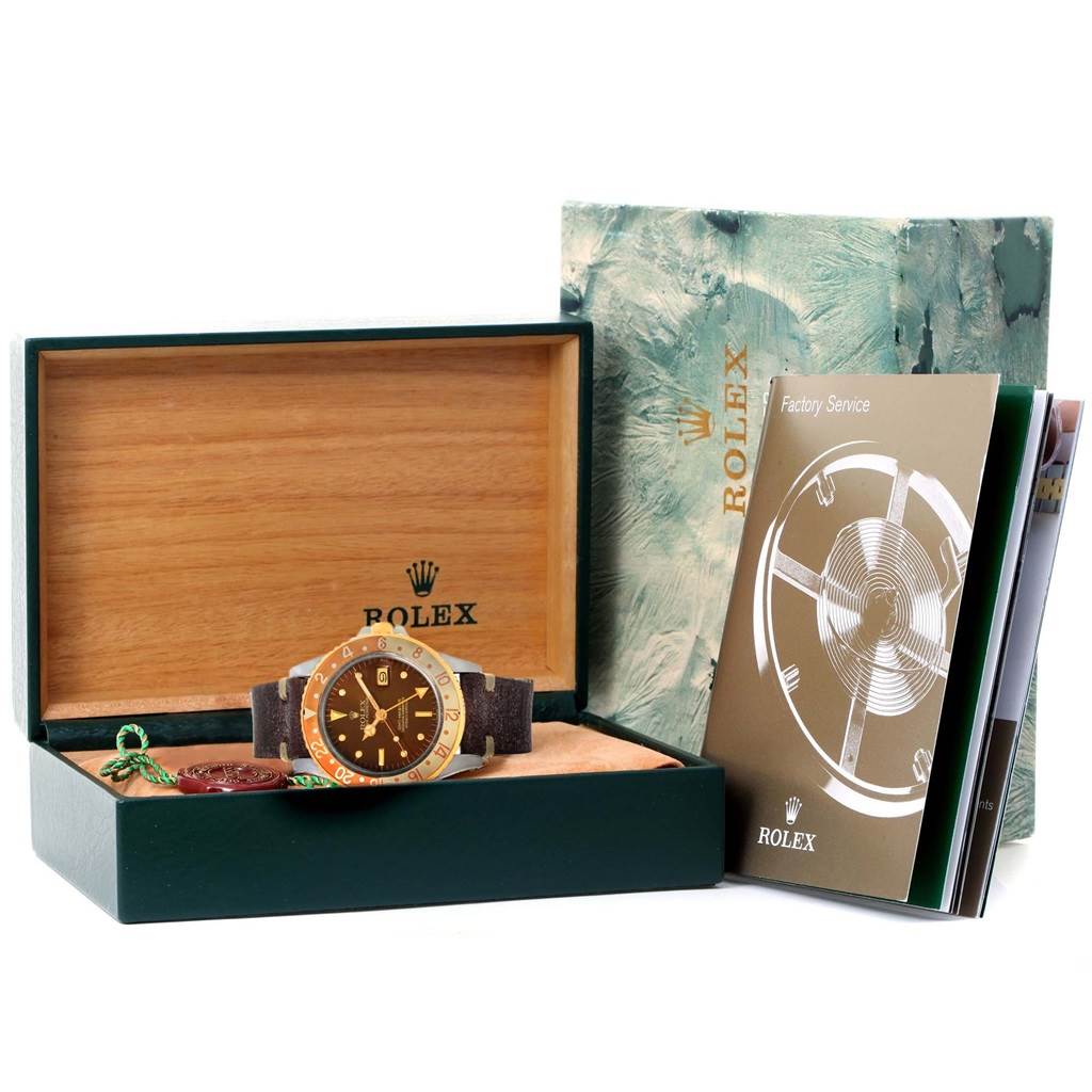 The image shows a GMT-Master Rolex watch in its open box with accompanying documents and accessories visible.