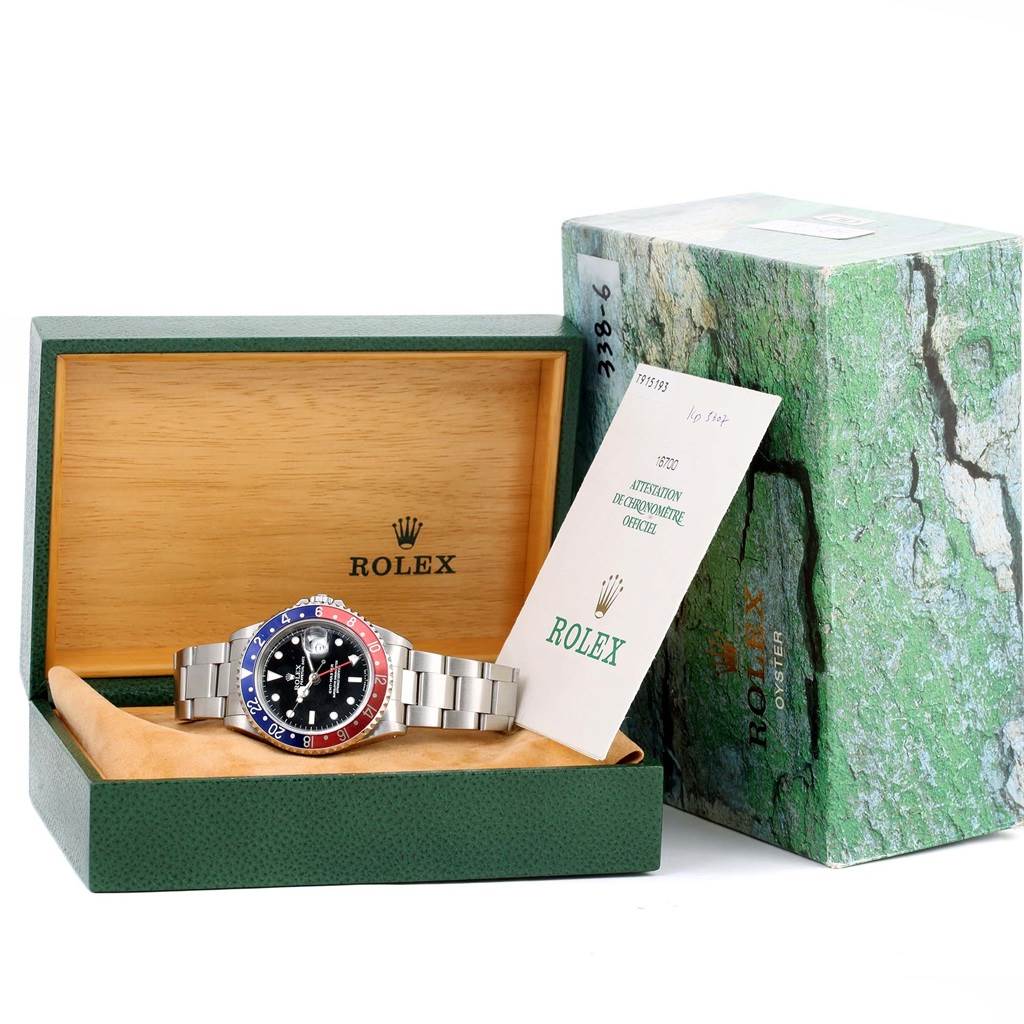 The image shows a Rolex GMT-Master 16700 Men's Stainless Steel Black Dial 16700 Men's Stainless Steel Black Dial watch in its box, accompanied by certification and original packaging.