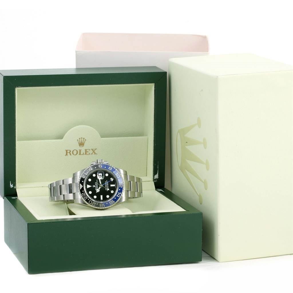 The Rolex GMT-Master 116710 Men
s Stainless Steel Black Dial 116710 Men
s Stainless Steel Black Dial watch is displayed at a front angle, housed in a green and beige Rolex box beside its outer packaging.