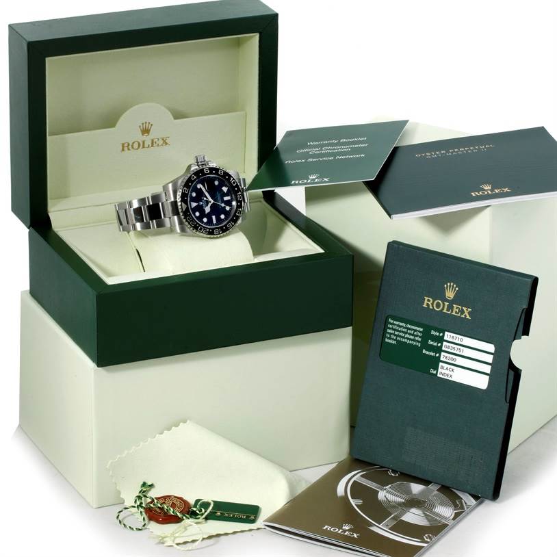 The image shows a Rolex GMT-Master 116710 Men
s Stainless Steel Black Dial 116710 Men
s Stainless Steel Black Dial watch displayed in its open box, along with accompanying manuals, hangtags, a cleaning cloth, and warranty card.