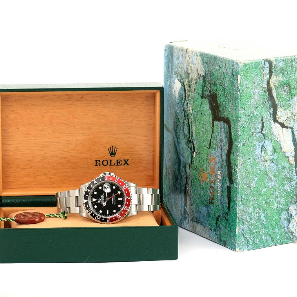 The image shows a Rolex GMT-Master 16710 Men's Stainless Steel Black Dial 16710 Men's Stainless Steel Black Dial watch placed inside an open green and wooden Rolex box with another closed box beside it.