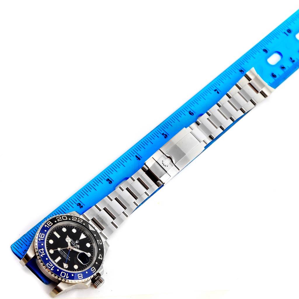 The Rolex GMT-Master 116710 Men's Stainless Steel Black Dial 116710 Men's Stainless Steel Black Dial watch is shown from a top view alongside a blue ruler, displaying the watch face, bezel, and metal bracelet.