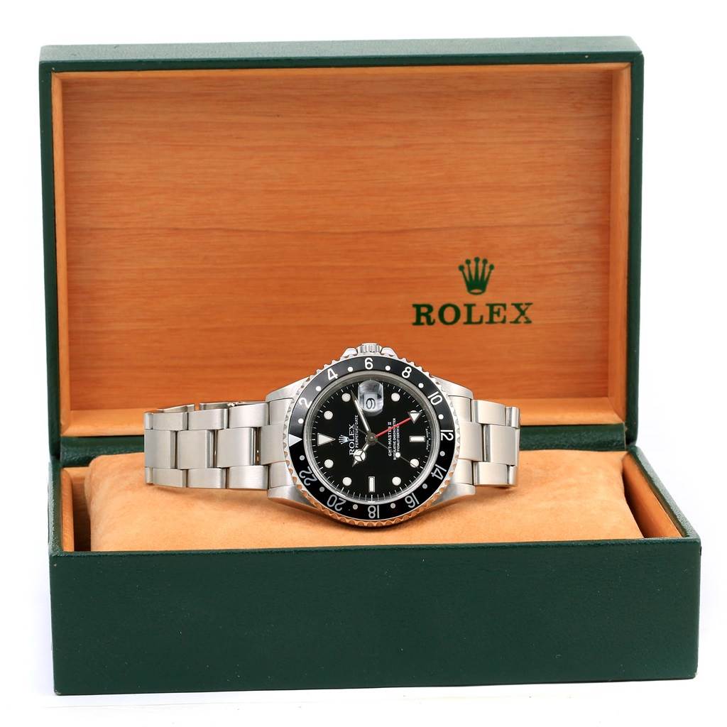 The Rolex GMT-Master 16710 Men's Stainless Steel Black Dial 16710 Men's Stainless Steel Black Dial watch is shown front and center in an open green and wood box.