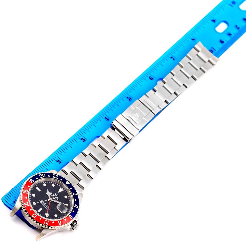 The image shows a Rolex GMT-Master 16710 Men's Stainless Steel Black Dial 16710 Men's Stainless Steel Black Dial watch, face-up, next to a blue ruler measuring the length of its metal bracelet.