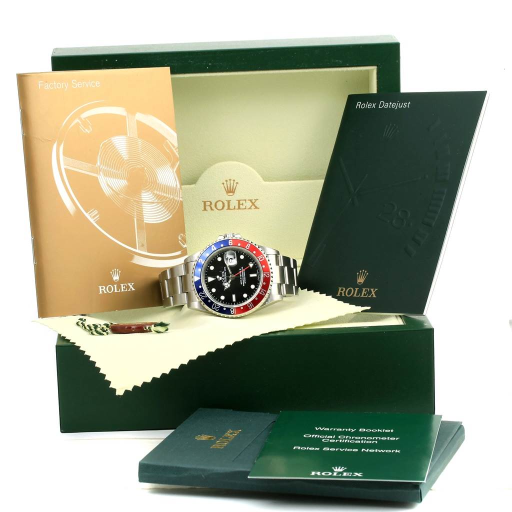 The Rolex GMT-Master 16710 Men's Stainless Steel Black Dial 16710 Men's Stainless Steel Black Dial watch is displayed at a front angle, along with its box, warranty booklet, and service manual.