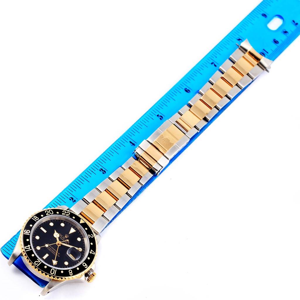 This image shows a top-down view of a Rolex GMT-Master 16713 Men's Stainless Steel Black Dial 16713 Men's Stainless Steel Black Dial watch with its bezel, dial, and metal bracelet against a ruler for scale.