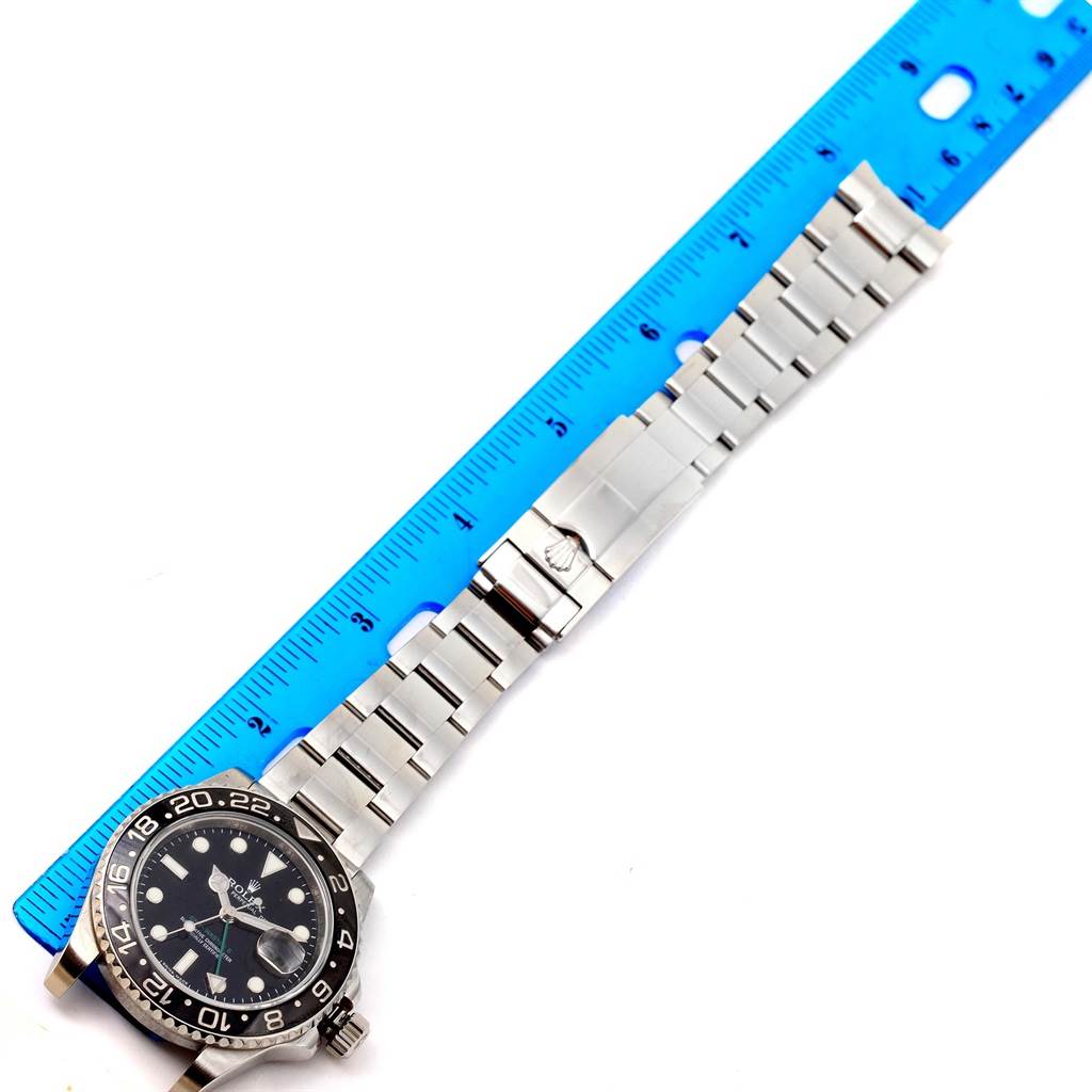 This image shows a top-down view of the Rolex GMT-Master 116710 Men's Stainless Steel Black Dial 116710 Men's Stainless Steel Black Dial watch, highlighting the face, bezel, bracelet, and clasp alongside a ruler.