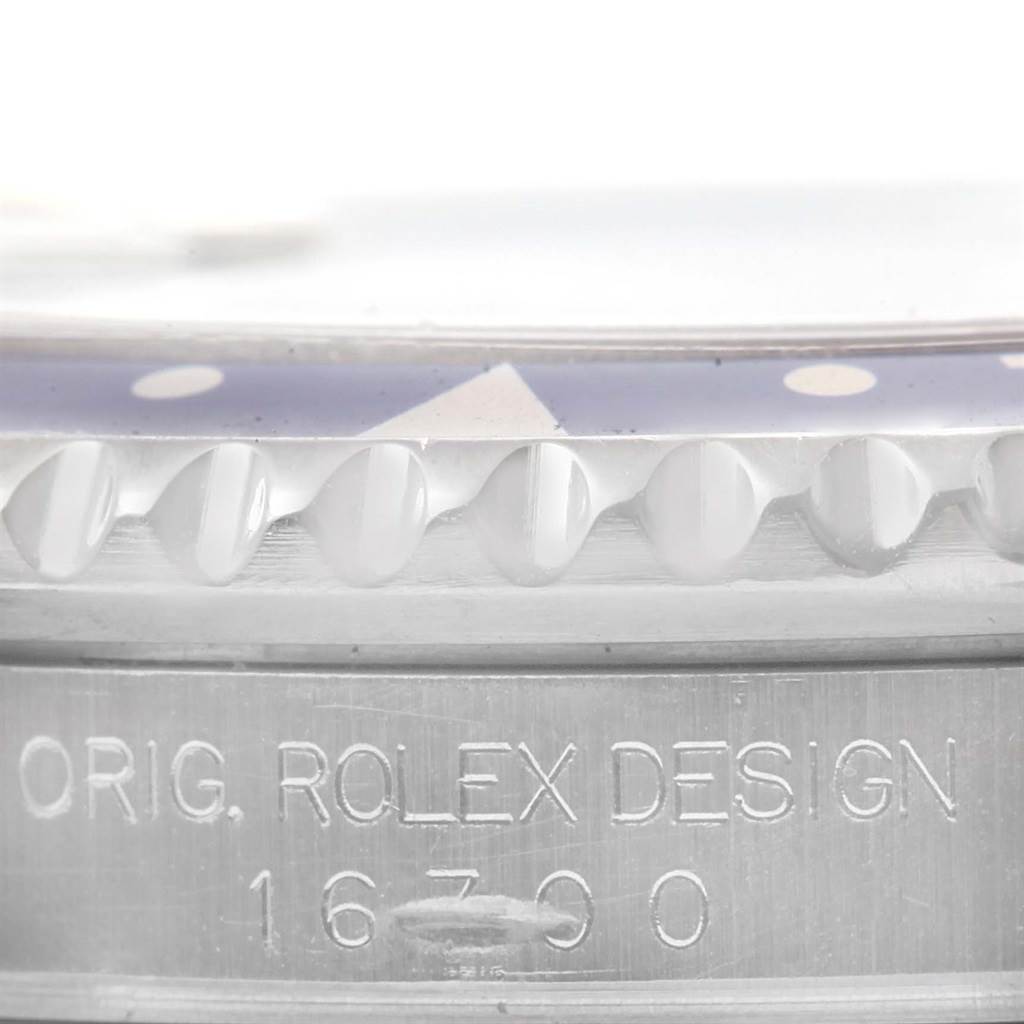 The image shows a close-up of the bezel and case side of a Rolex GMT-Master 16700 Men's Stainless Steel Black Dial 16700 Men's Stainless Steel Black Dial watch with the design number visible.