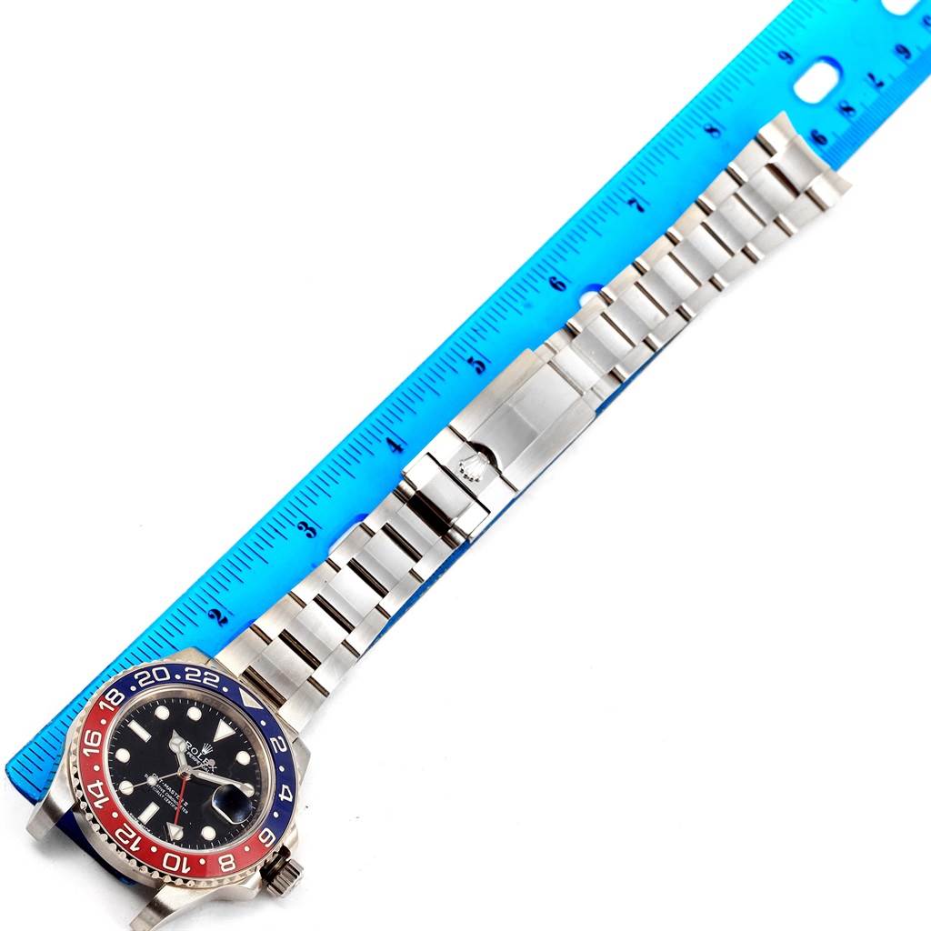 The image shows a Rolex GMT-Master 116719 Men
s White Gold Black Dial 116719 Men
s White Gold Black Dial watch with a "Pepsi" bezel placed next to a ruler, displaying its face and metal bracelet.