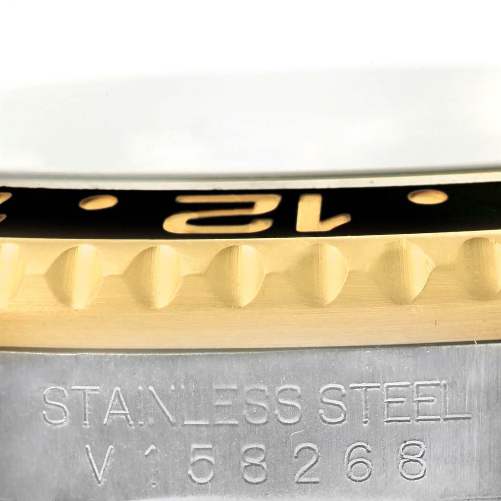 The image shows a close-up of the Rolex GMT-Master 116713 Men's Stainless Steel Black Dial 116713 Men's Stainless Steel Black Dial watch's bezel and stainless steel casing, including part of its serial number.