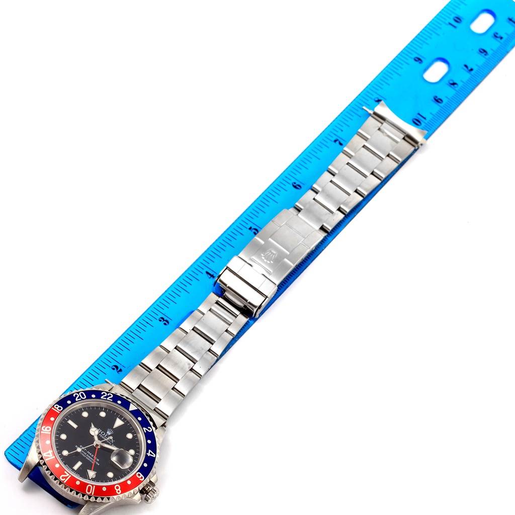 The image shows a Rolex GMT-Master 16700 Men's Stainless Steel Black Dial 16700 Men's Stainless Steel Black Dial watch positioned alongside a blue ruler, highlighting the entire watch band and face.