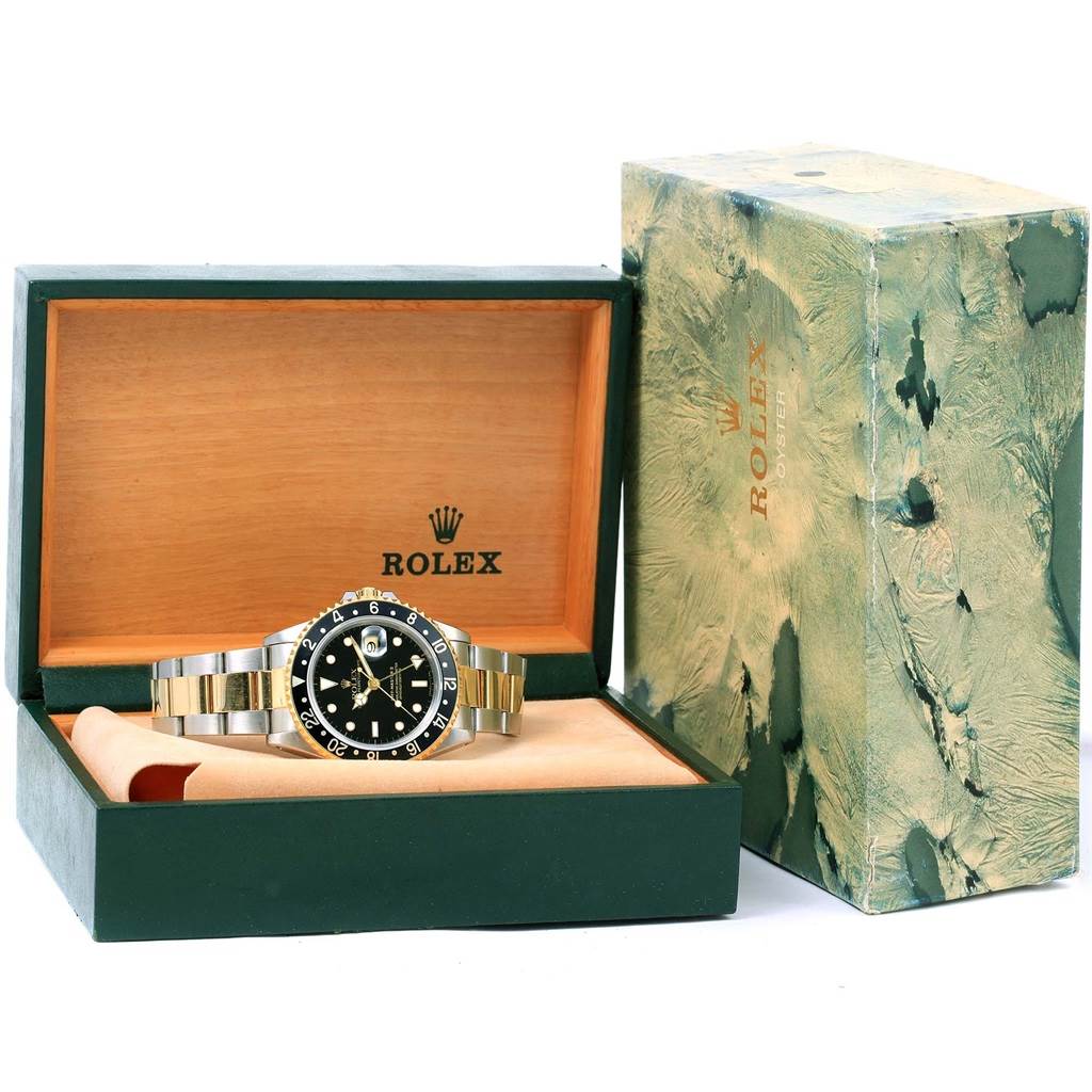 The Rolex GMT-Master 16713 Men's Stainless Steel Black Dial 16713 Men's Stainless Steel Black Dial watch is displayed front-on in an open wooden box, with the lid and outer green box also visible.