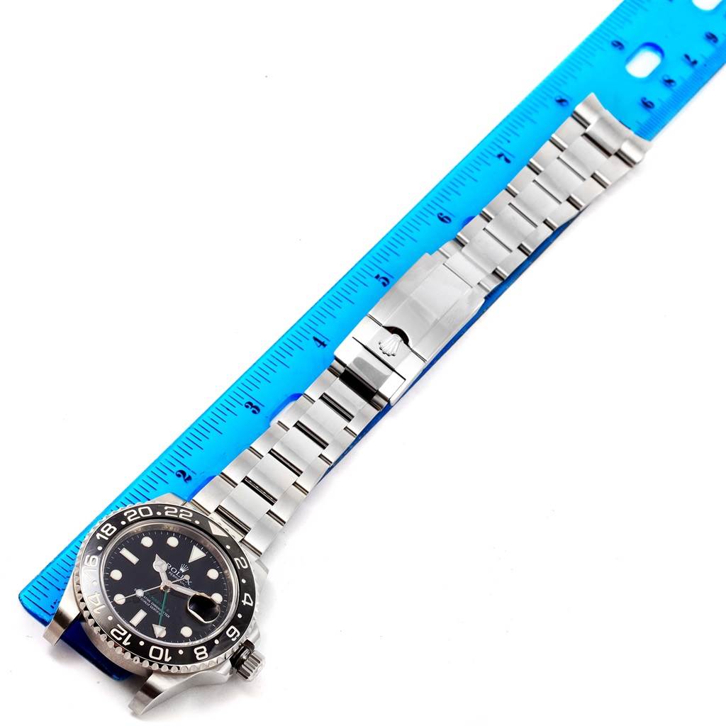 This image shows a Rolex GMT-Master 116710 Men's Stainless Steel Black Dial 116710 Men's Stainless Steel Black Dial watch laid flat next to a blue ruler, displaying its face, bezel, and bracelet.