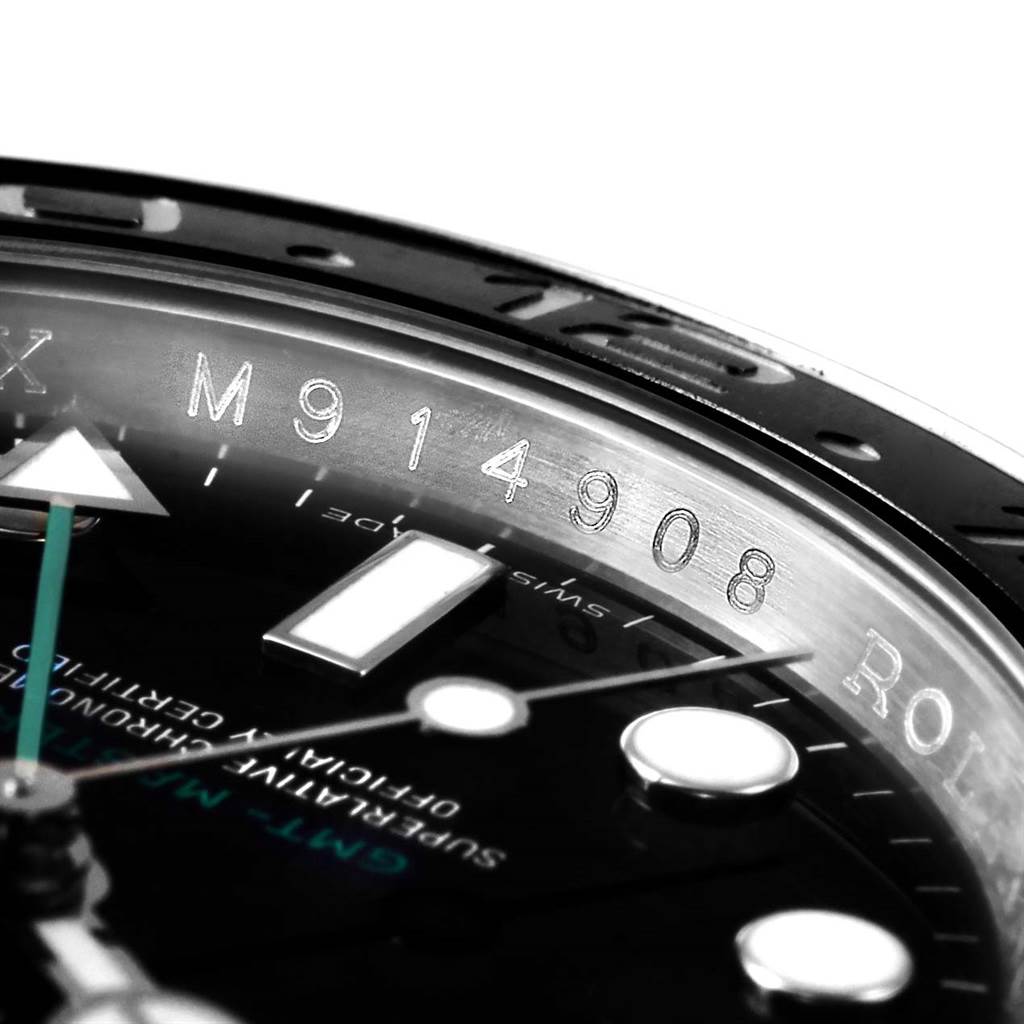 This close-up image of a Rolex GMT-Master 116710 Men's Stainless Steel Black Dial 116710 Men's Stainless Steel Black Dial watch shows the serial number, part of the bezel, and parts of the dial and hands.