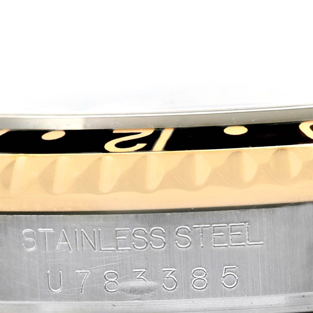 This close-up image of a Rolex GMT-Master 16713 Men's Stainless Steel Black Dial 16713 Men's Stainless Steel Black Dial watch shows part of the bezel, dial, and the engraved stainless steel case.