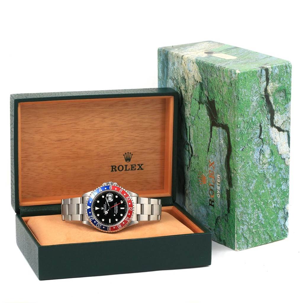 The Rolex GMT-Master 16710 Men's Stainless Steel Black Dial 16710 Men's Stainless Steel Black Dial watch is shown from the front, inside its open green and wooden box with its original packaging.
