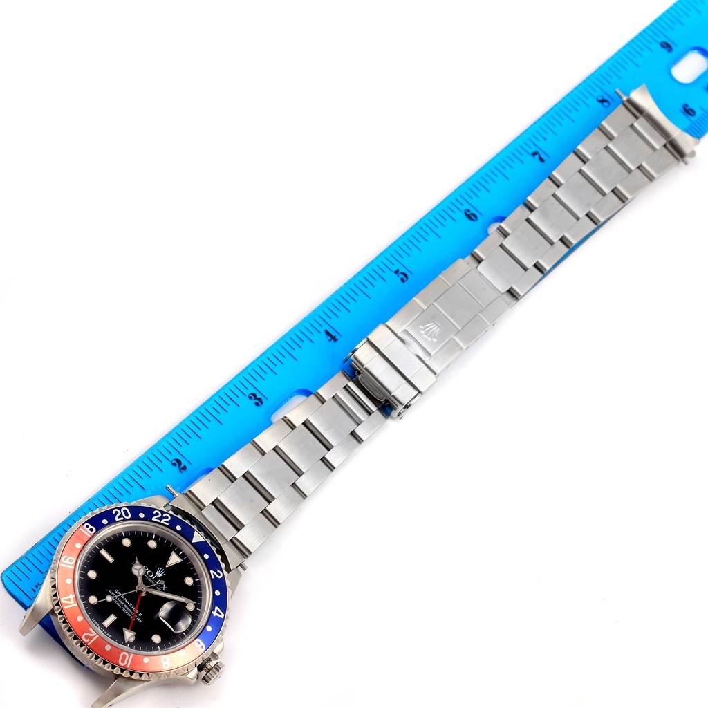 The image shows a top-down view of a Rolex GMT-Master 16710 Men's Stainless Steel Black Dial 16710 Men's Stainless Steel Black Dial watch with a "Pepsi" bezel, next to a blue ruler for scale.