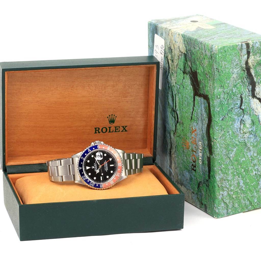 The Rolex GMT-Master 16700 Men's Stainless Steel Black Dial 16700 Men's Stainless Steel Black Dial watch is shown front-facing inside its open box, next to a closed box with a green marbled pattern.