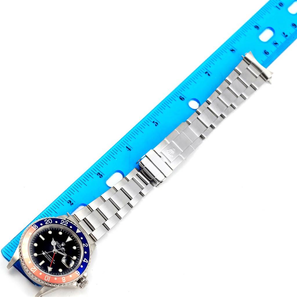 The image shows a Rolex GMT-Master 16700 Men's Stainless Steel Black Dial 16700 Men's Stainless Steel Black Dial watch from a top-down angle, including its bezel, face, and entire bracelet next to a blue ruler.