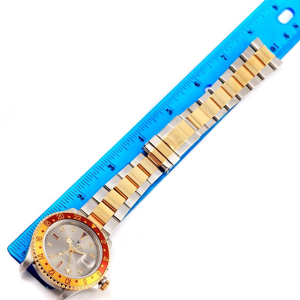 The Rolex GMT-Master 16713 Men's Stainless Steel Grey Dial 16713 Men's Stainless Steel Grey Dial watch is shown from a top-down angle, with its bezel, dial, and bracelet next to a ruler for scale.