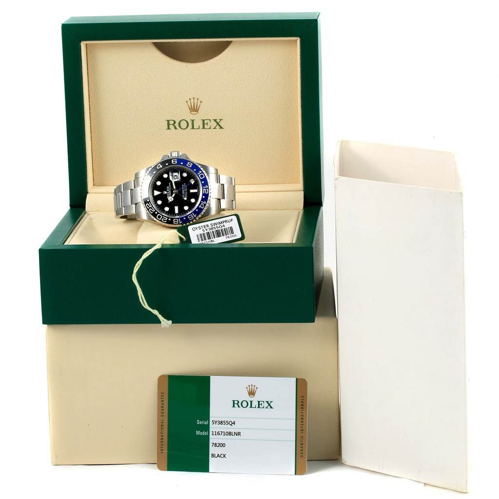 The Rolex GMT-Master 116710 Men's Stainless Steel Black Dial 116710 Men's Stainless Steel Black Dial watch is shown in a front view, placed inside its green box with an open card detailing its model and serial number.