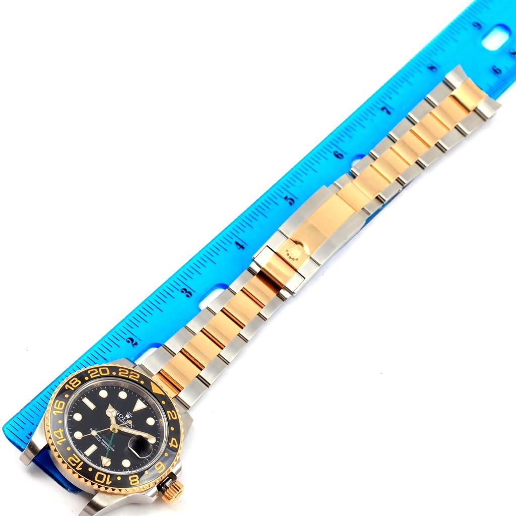 The image shows a Rolex GMT-Master 116713 Men
s Stainless Steel Black Dial 116713 Men
s Stainless Steel Black Dial watch laid flat beside a blue ruler, highlighting the face, bezel, and bracelet.