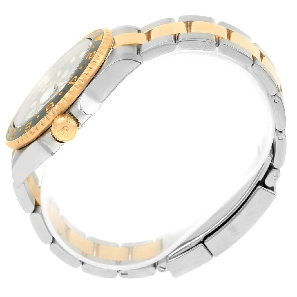 The image shows a side view of a Rolex GMT-Master 116713 Men
s Stainless Steel Black Dial 116713 Men
s Stainless Steel Black Dial, focusing on its bezel, crown, and two-tone bracelet.