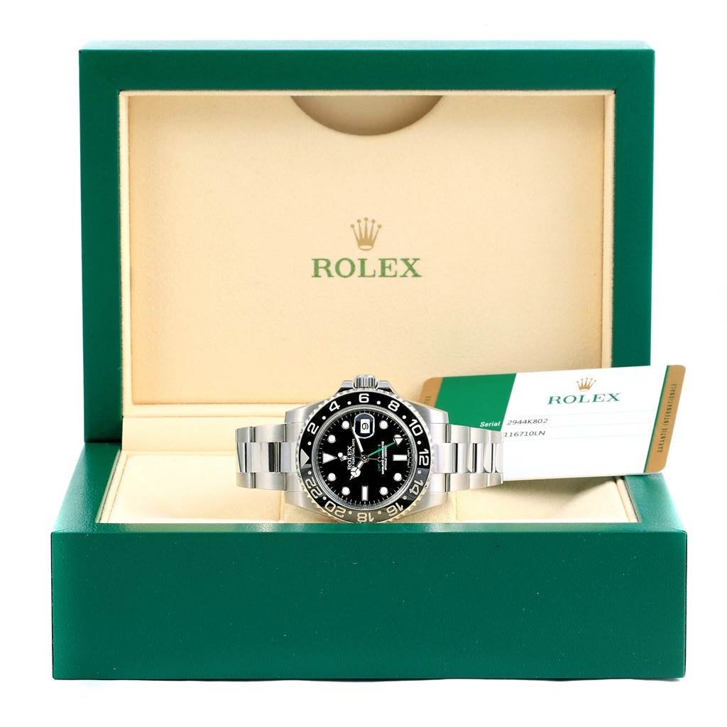 The Rolex GMT-Master 116710 Men's Stainless Steel Black Dial 116710 Men's Stainless Steel Black Dial watch is displayed front-on in an open box with its warranty card beside it.