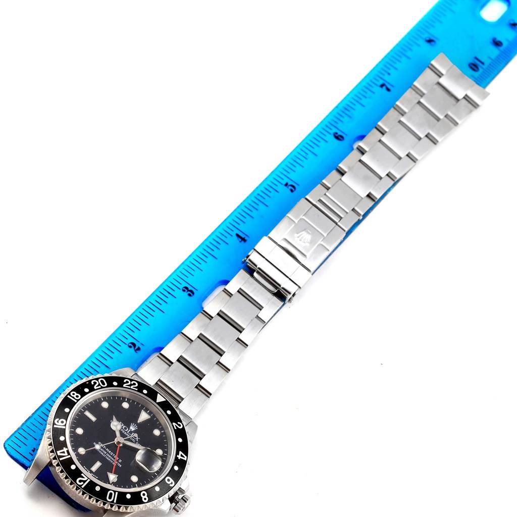 This image shows a top view of a Rolex GMT-Master 16710 Men's Stainless Steel Black Dial 16710 Men's Stainless Steel Black Dial watch with a metal bracelet next to a blue ruler for scale.