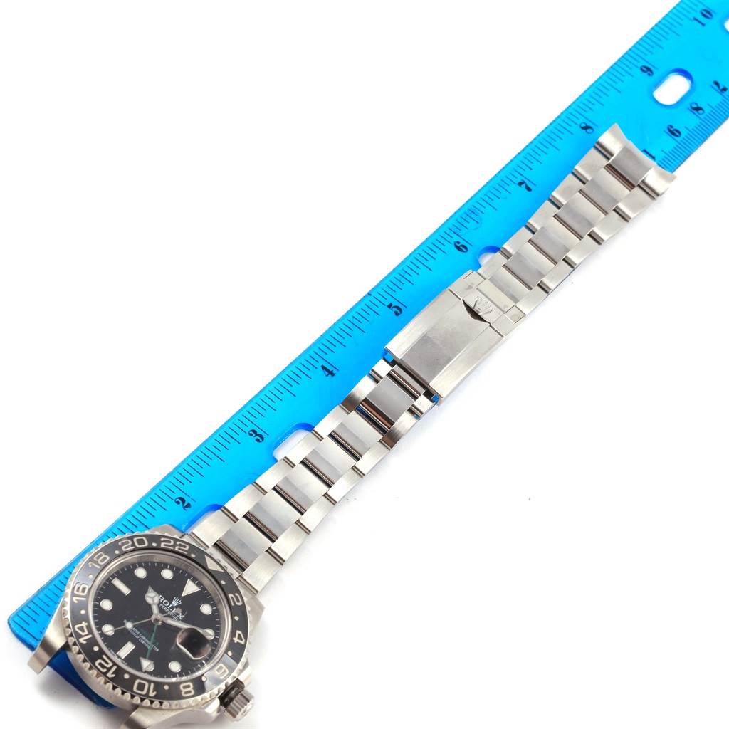 The image shows a Rolex GMT-Master 116710 Men
s Stainless Steel Black Dial 116710 Men
s Stainless Steel Black Dial watch, with the watch face and metal bracelet laid next to a blue ruler from a top-down angle.