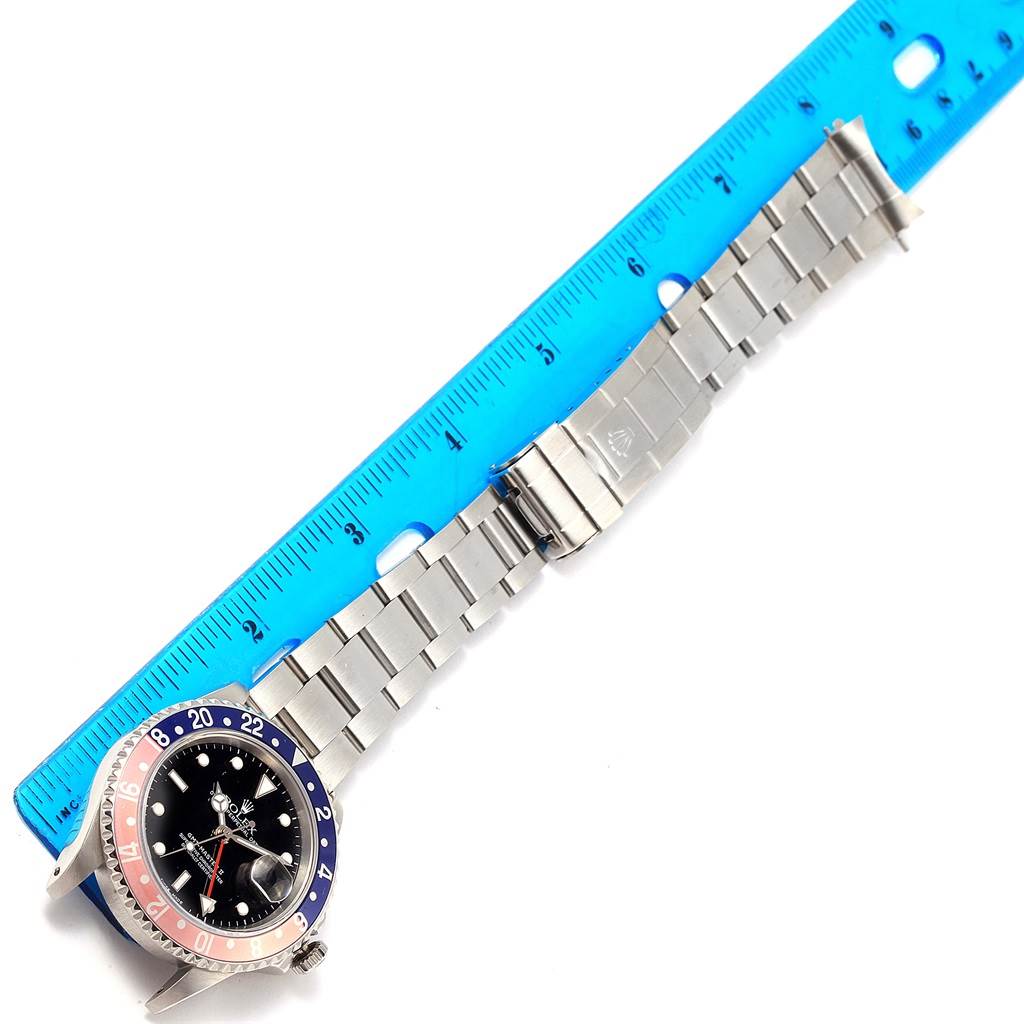 This image shows the Rolex GMT-Master 16710 Men's Stainless Steel Black Dial 16710 Men's Stainless Steel Black Dial watch and its entire bracelet laid flat next to a ruler, viewed from above.