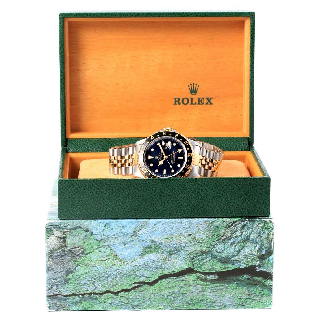 The Rolex GMT-Master 16713 Men's Stainless Steel Black Dial 16713 Men's Stainless Steel Black Dial watch is shown front-facing in an open green and wooden box.