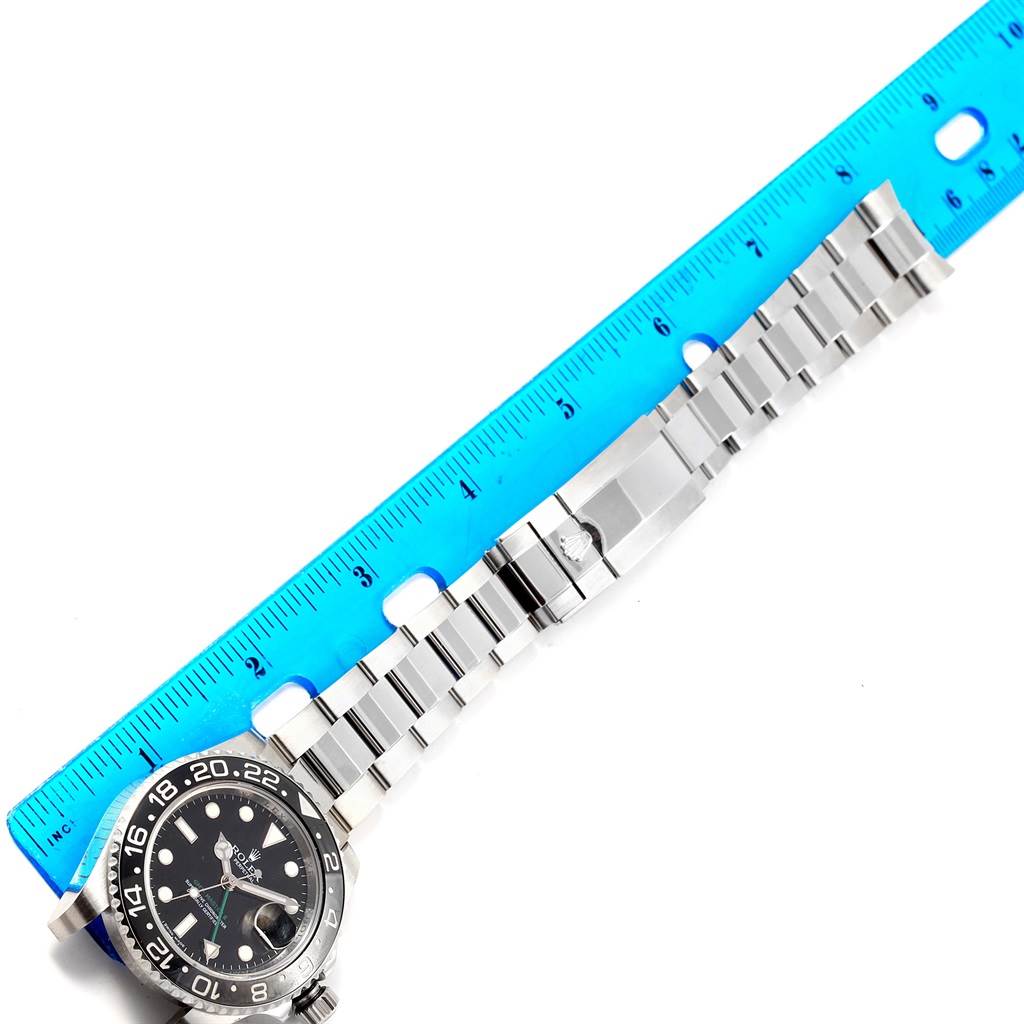 This image shows the Rolex GMT-Master 116710 Men's Stainless Steel Black Dial 116710 Men's Stainless Steel Black Dial watch laid next to a ruler, highlighting the watch face and metal bracelet.