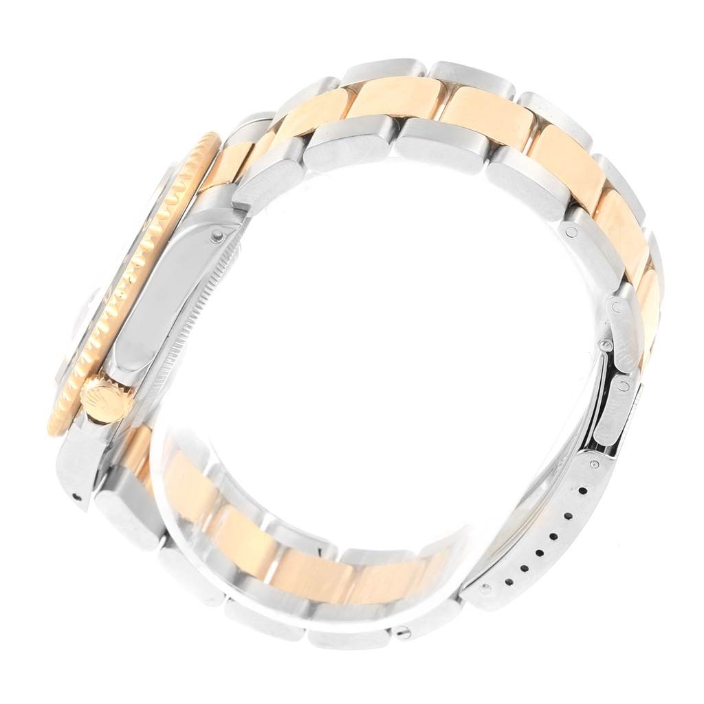 The image shows a side view of a Rolex GMT-Master 16713 Men
s Stainless Steel Black Dial 16713 Men
s Stainless Steel Black Dial watch, highlighting the gold bezel, crown, and two-tone bracelet.