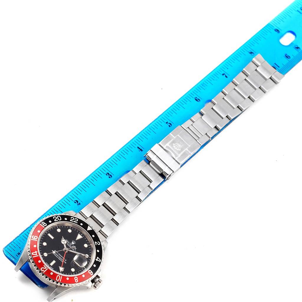 The image shows a Rolex GMT-Master 16710 Men's Stainless Steel Black Dial 16710 Men's Stainless Steel Black Dial watch laid flat next to a ruler, highlighting its bezel, face, and bracelet clasp.