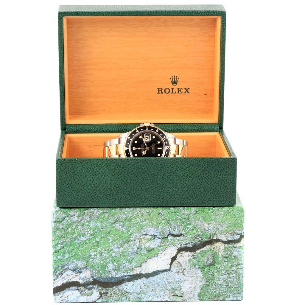 The Rolex GMT-Master 16713 Men's Stainless Steel Black Dial 16713 Men's Stainless Steel Black Dial watch is shown in a front view inside its open green and wood-accented box.
