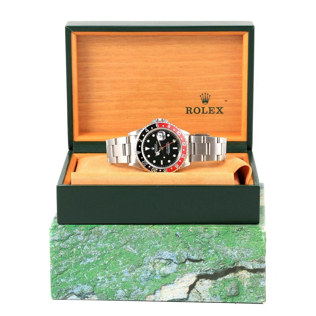 The Rolex GMT-Master 16700 Men's Stainless Steel Black Dial 16700 Men's Stainless Steel Black Dial watch is displayed inside its open green and wood-tone box, showing the face, bezel, and bracelet.