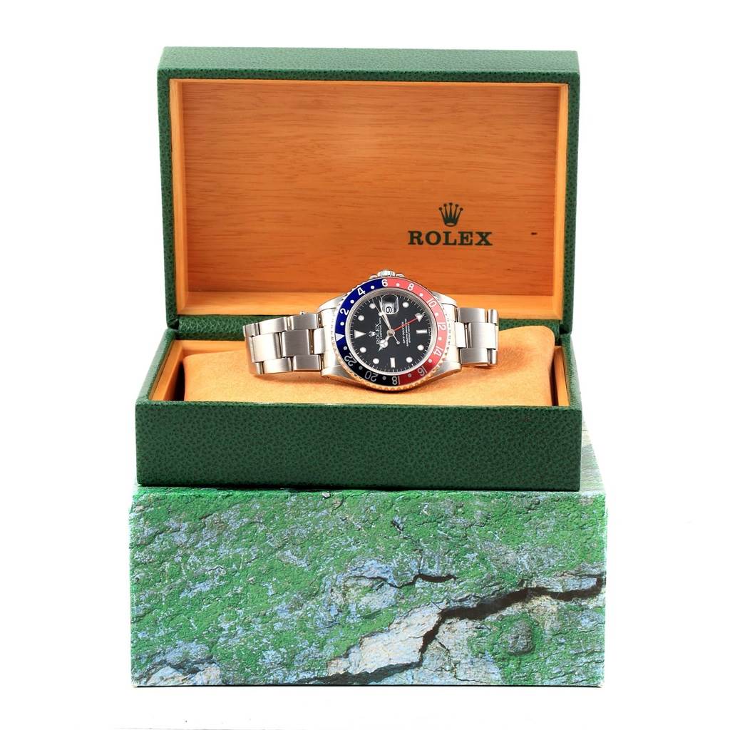 The image shows a Rolex GMT-Master 16700 Men's Stainless Steel Black Dial 16700 Men's Stainless Steel Black Dial watch inside its green display box, highlighting the face, bezel, and bracelet.