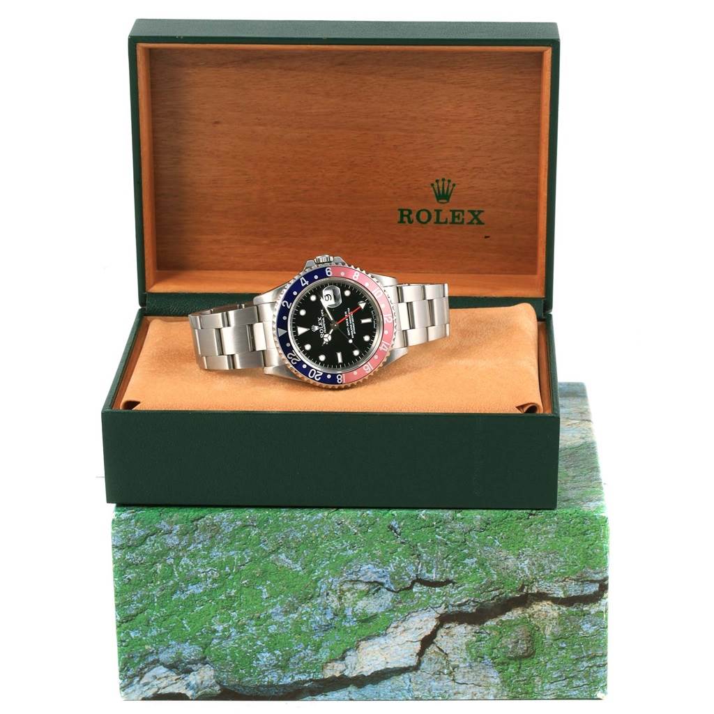 The Rolex GMT-Master 16700 Men's Stainless Steel Black Dial 16700 Men's Stainless Steel Black Dial watch is shown front-facing, positioned inside its open box on a cushion.
