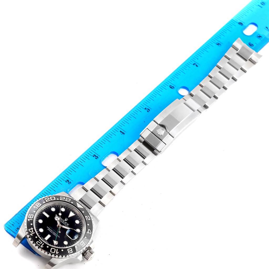 The image shows a Rolex GMT-Master 116710 Men
s Stainless Steel Black Dial 116710 Men
s Stainless Steel Black Dial watch with its bracelet fully extended and measured against a blue ruler.