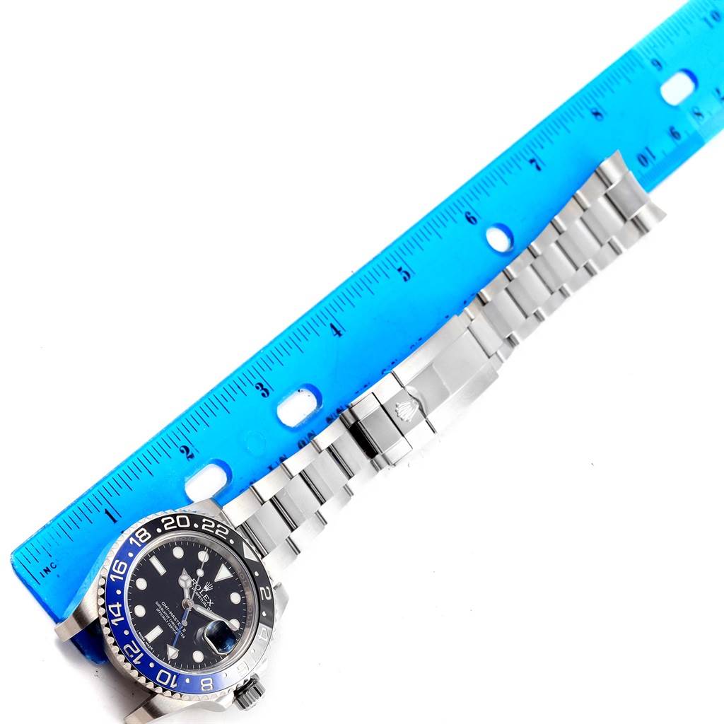 The image shows a Rolex GMT-Master 116710 Men
s Stainless Steel Black Dial 116710 Men
s Stainless Steel Black Dial watch and its bracelet from above, measured alongside a blue ruler.