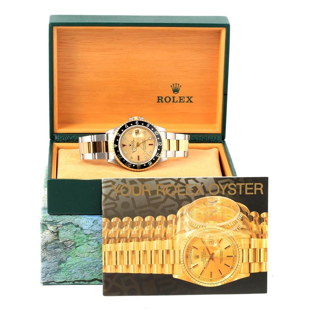 The Rolex GMT-Master 16713 Men's Stainless Steel Champagne Dial 16713 Men's Stainless Steel Champagne Dial watch is shown from the front, inside its green and beige presentation box with an information booklet in front.