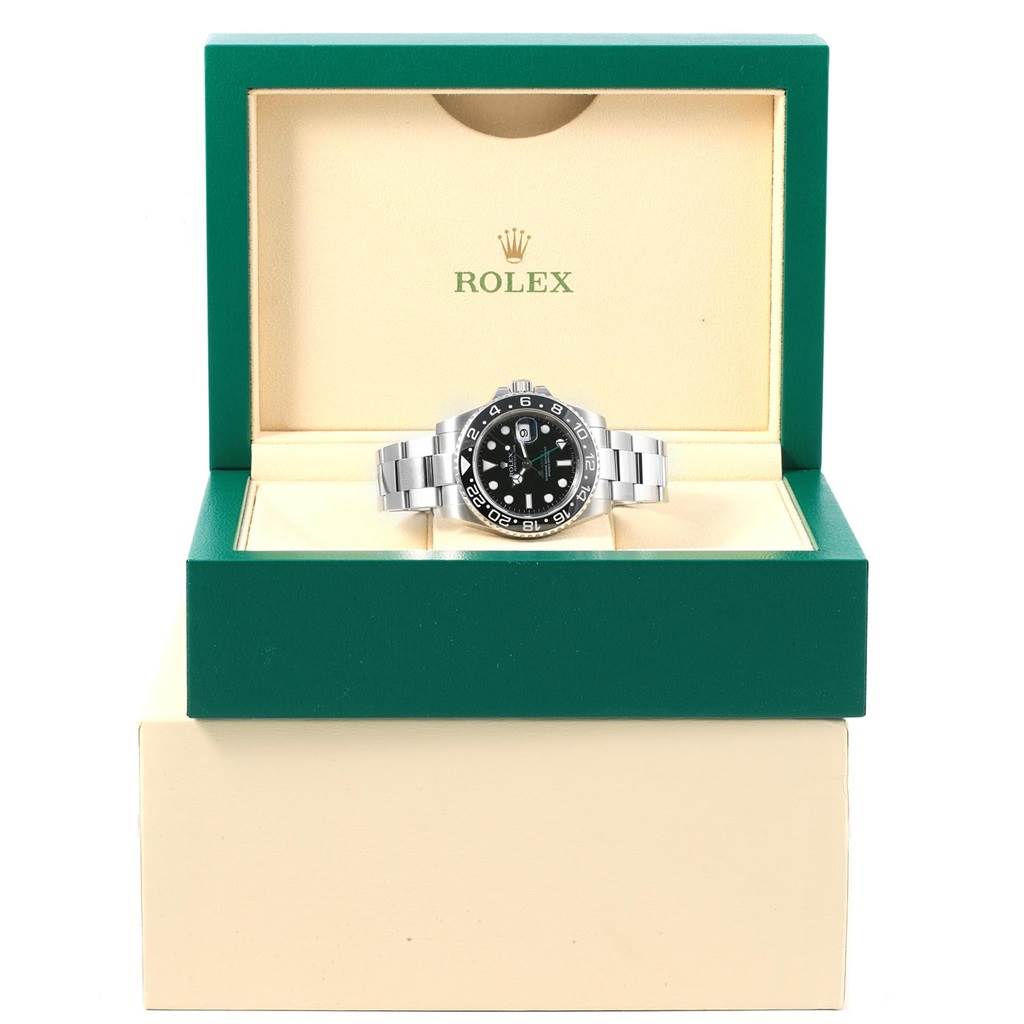 The Rolex GMT-Master 116710 Men
s Stainless Steel Black Dial 116710 Men
s Stainless Steel Black Dial watch is pictured from the front, displayed in an open green and beige Rolex box.