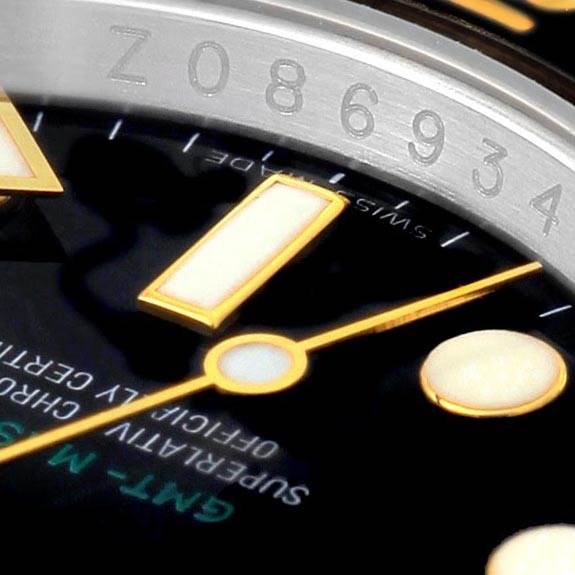This close-up image of a Rolex GMT-Master 116713 Men
s Stainless Steel Black Dial 116713 Men
s Stainless Steel Black Dial watch shows part of the dial, hour markers, and the edge of the bezel with engraved numbers.