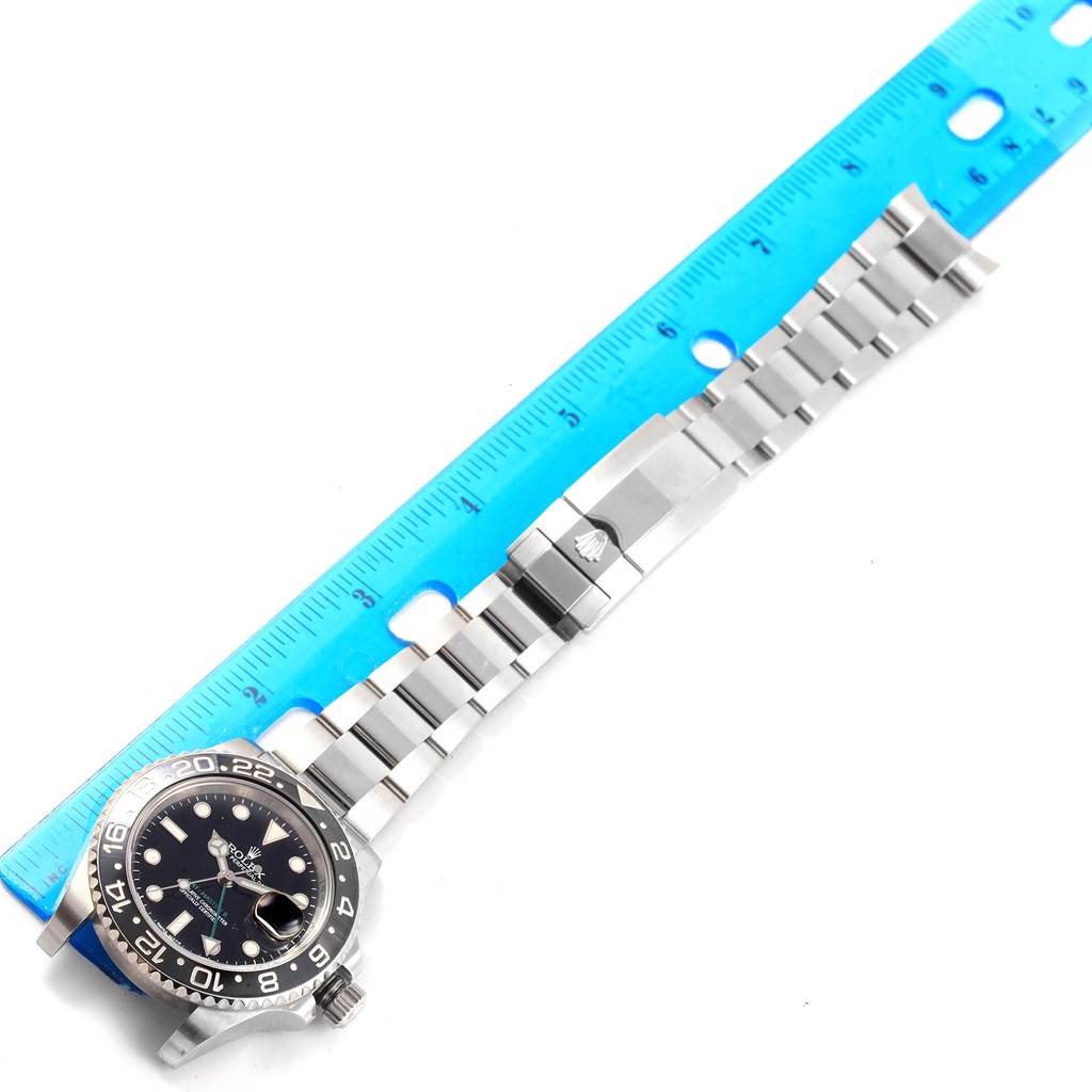This image shows a top-down view of a Rolex GMT-Master 116710 Men's Stainless Steel Black Dial 116710 Men's Stainless Steel Black Dial watch face, band, and clasp next to a ruler for measurement.