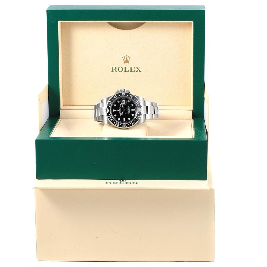 The Rolex GMT-Master 116710 Men's Stainless Steel Black Dial 116710 Men's Stainless Steel Black Dial watch is shown front-facing, inside an open green and beige branded case.
