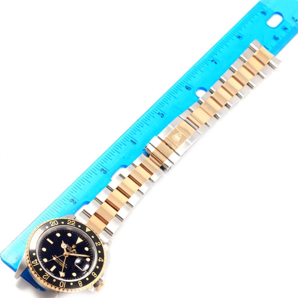 The image shows a Rolex GMT-Master 16713 Men's Stainless Steel Black Dial 16713 Men's Stainless Steel Black Dial watch laying flat next to a blue ruler, highlighting the watch's bracelet and face.